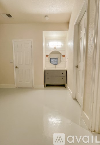 A hallway with a white door and a small table with a clock on it.
