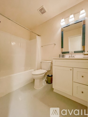 A white bathroom with a toilet, sink and mirror.