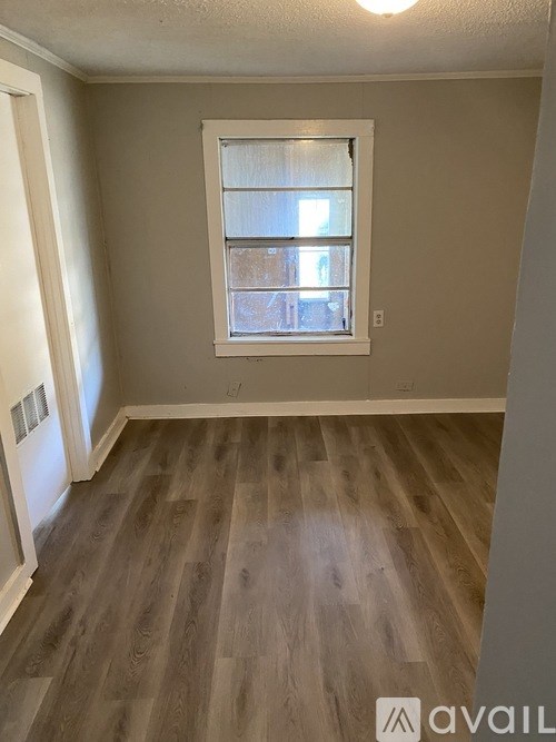 A room with a window and wooden flooring.