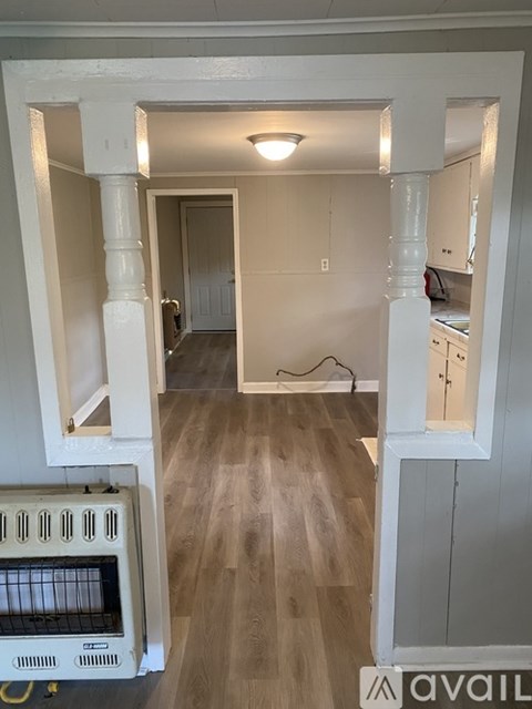 A kitchen with white cabinets and a wooden floor.