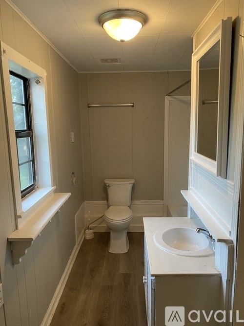 A bathroom with a toilet, sink, and window.