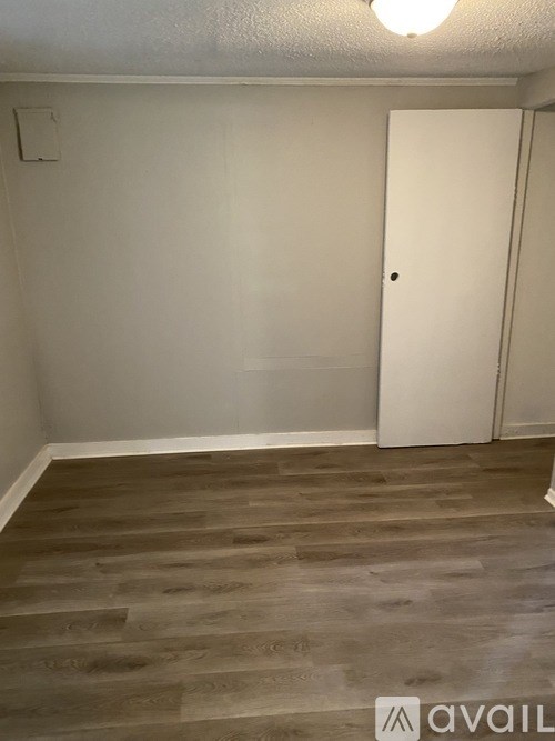 A room with a white door and wooden flooring.