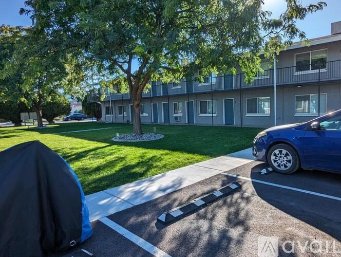 A blue car is parked on the side of a road in front of a building.