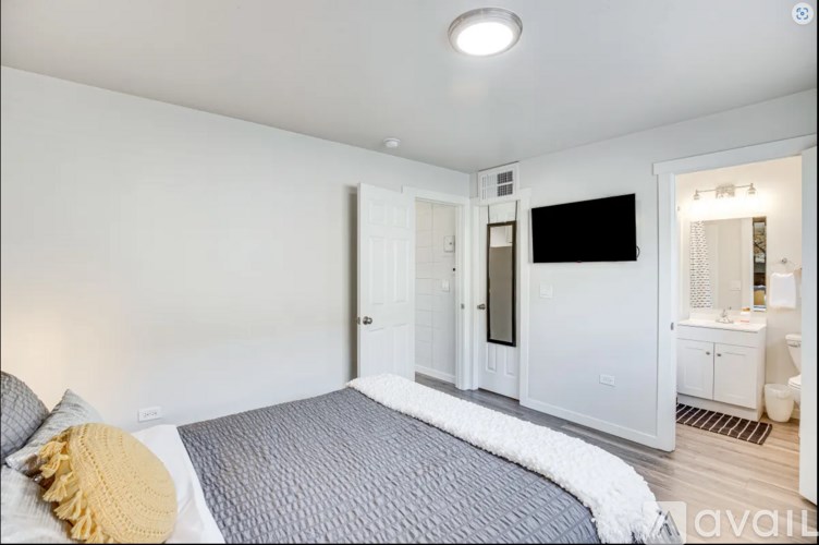 A bedroom with a bed, a television, and a bathroom visible through the door.