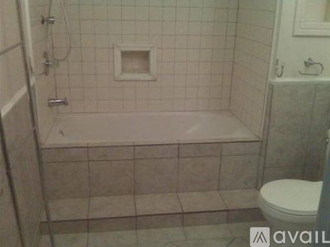 A bathroom with a white toilet and a bathtub with a shower head.