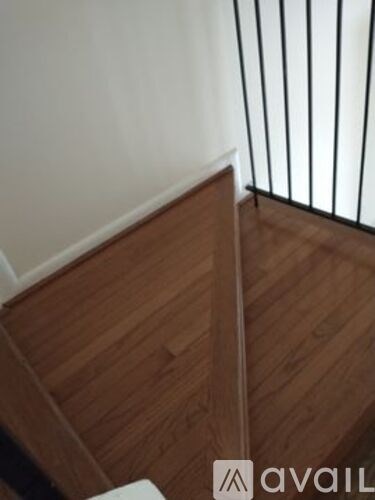 A wooden floor with a white wall and a black metal railing.