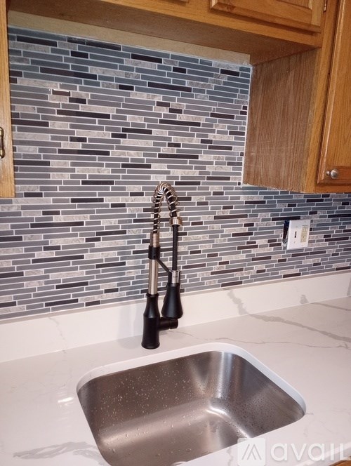 A kitchen with a sink and a backsplash made of tiles.
