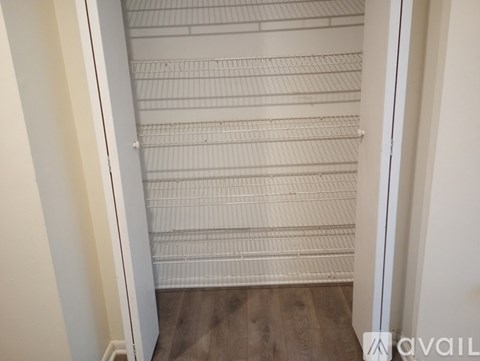 A white closet with shelves and a wooden floor.