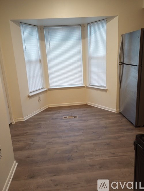 A kitchen with a refrigerator and wooden flooring.