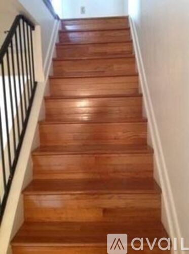 A wooden staircase with a black railing.