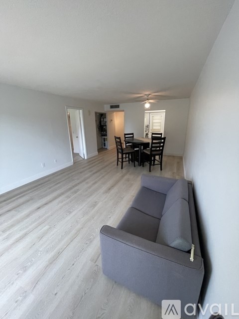 A living room with a grey couch and a dining table with chairs.
