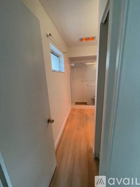A hallway with a wooden floor and white walls.