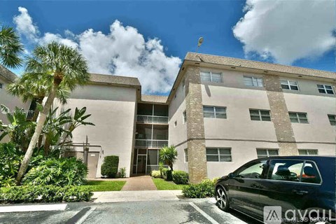 A black car is parked in front of a building with a sign that reads "avail.".