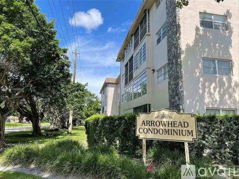 A sign for Arrowhead Condominium stands in front of a building.