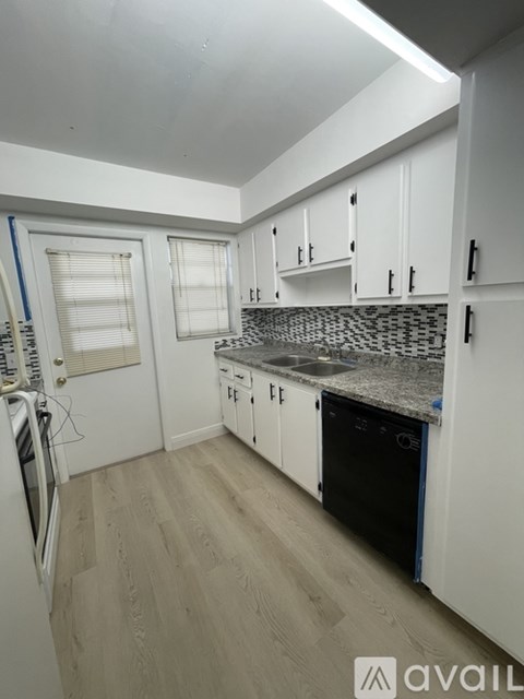 A kitchen with white cabinets and a black dishwasher.