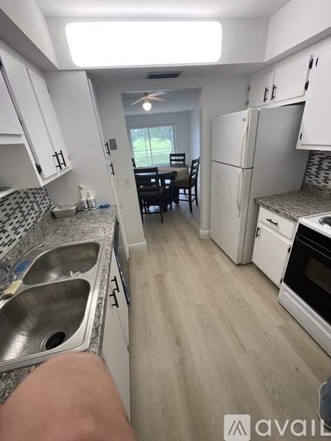 A kitchen with a white fridge and a dining table with chairs.