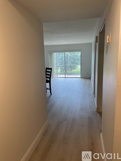 A hallway with a chair and a door leading to a balcony.
