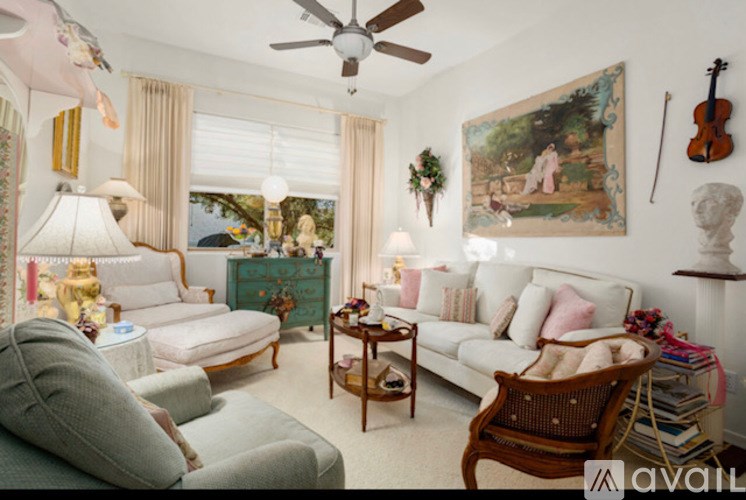 A living room with a white couch, a green dresser, and a painting on the wall.