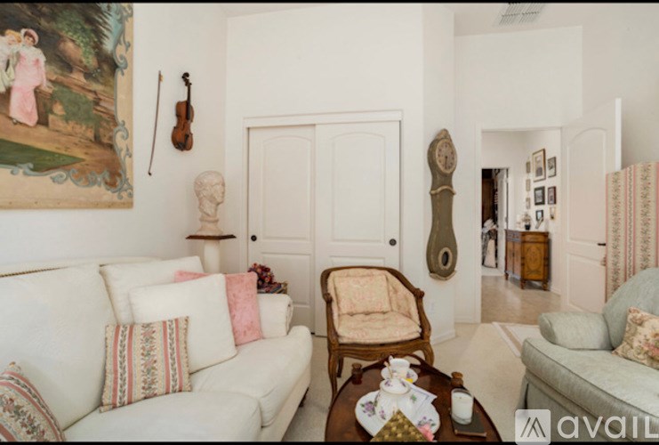 A living room with a white couch and a painting on the wall.