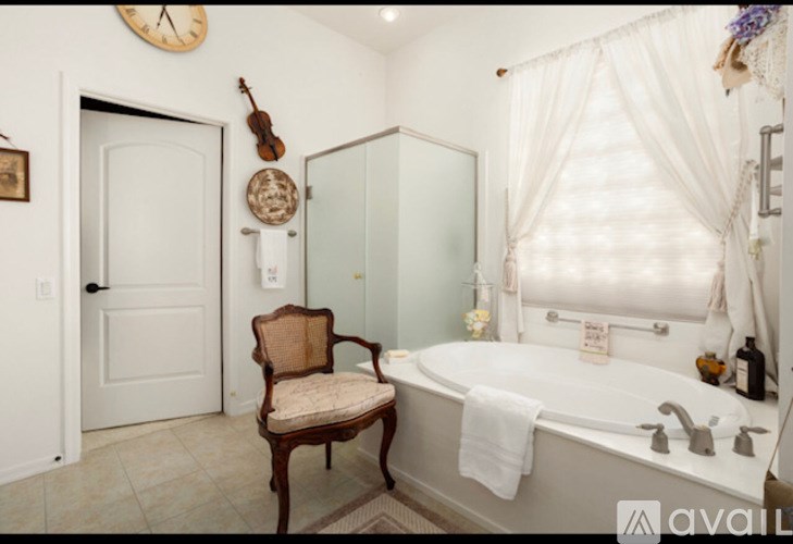 A bathroom with a white tub, a chair, and a clock on the wall.