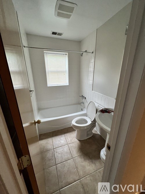 A small bathroom with a toilet, tub, and window.