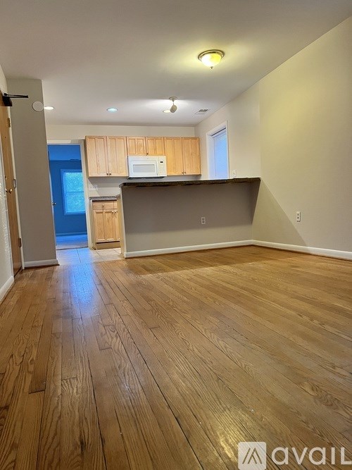 A room with wooden flooring and a kitchenette.