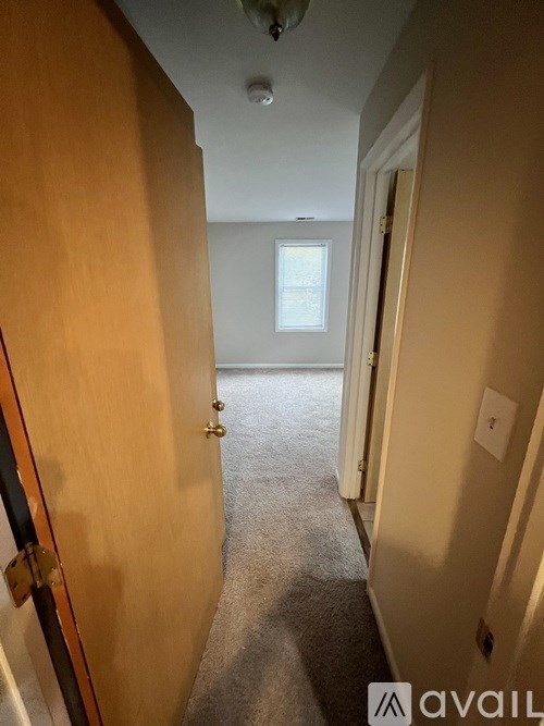 A hallway with a closed door on the left and an open door on the right.
