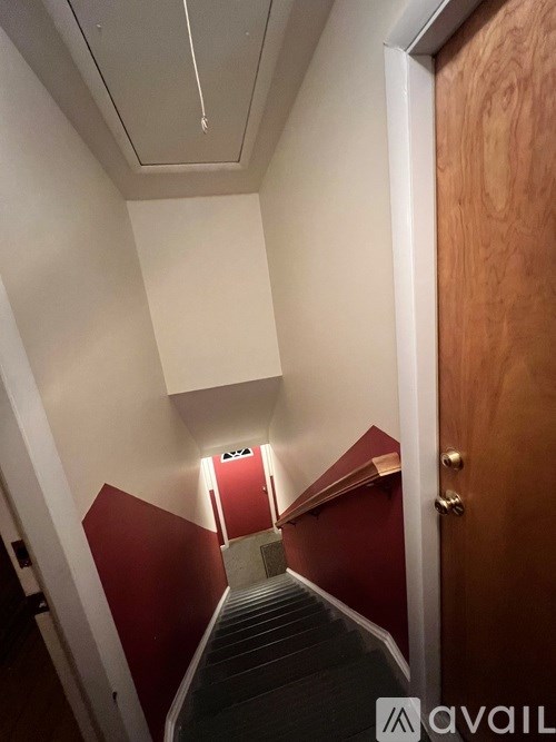 A staircase with a red wall on the side and a wooden door on the other side.