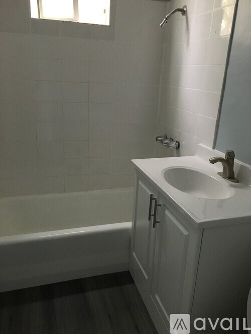 A white bathroom with a tub, sink, and mirror.