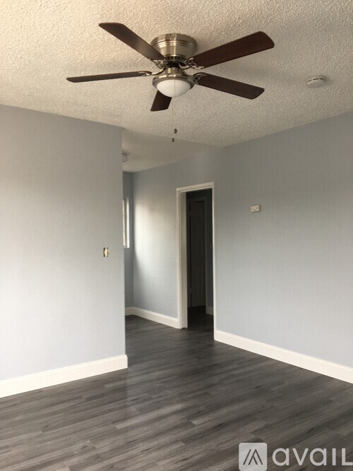 A room with a ceiling fan and wooden flooring.