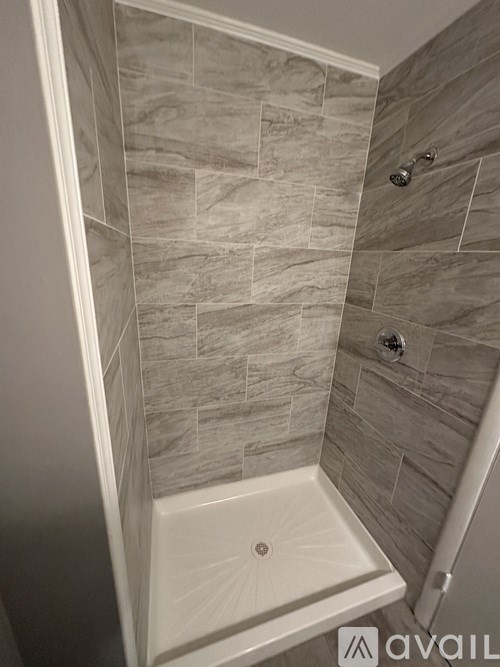 A shower area with a tiled wall and floor.