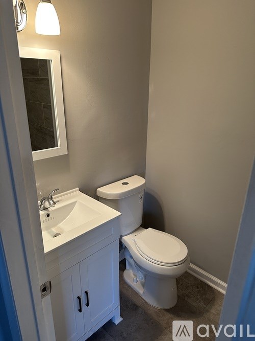 A bathroom with a toilet, sink, and cabinet.