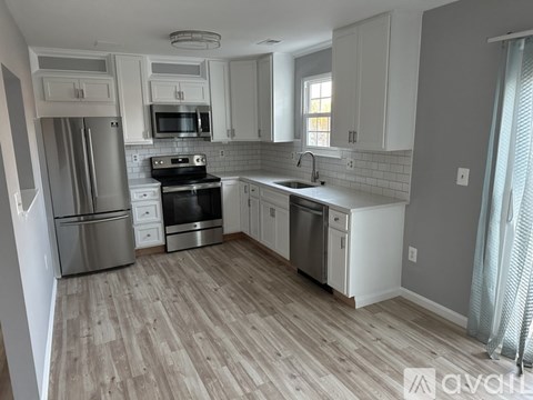 A kitchen with white cabinets and a wooden floor.