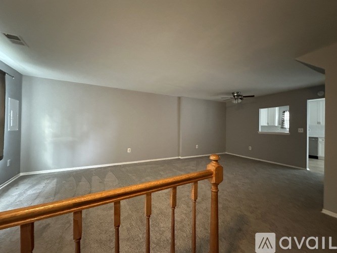 A spacious empty room with a wooden railing on the left side.
