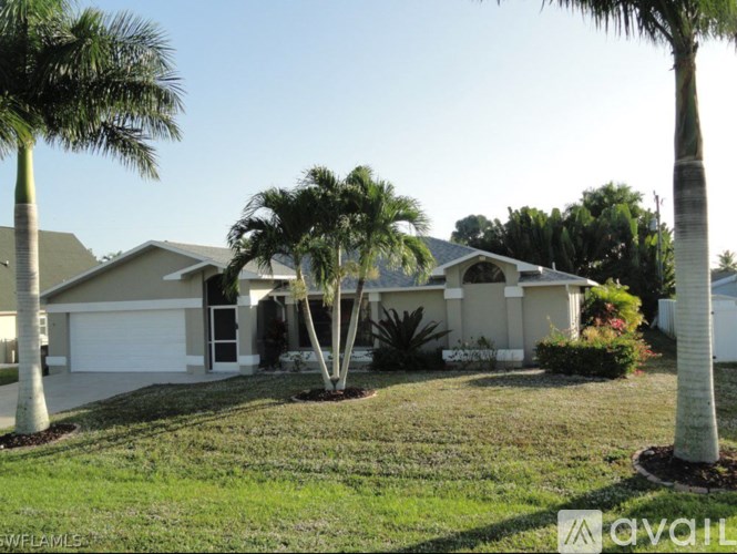 A house with a white garage door is surrounded by palm trees.