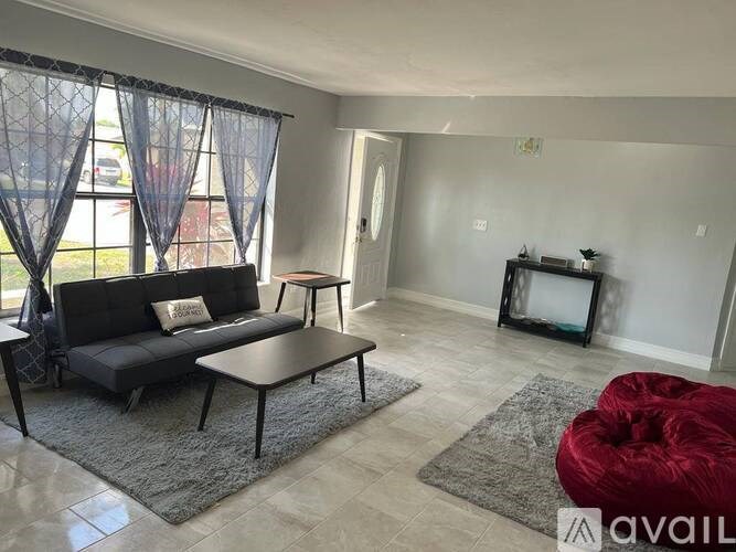 A living room with a black sofa, a grey coffee table, and a red bean bag chair.