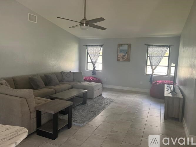 A living room with a couch, a coffee table, and a ceiling fan.