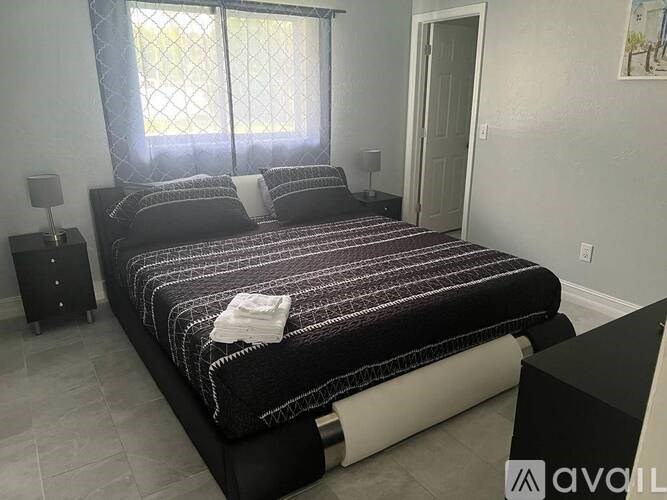 A bedroom with a large bed and a window with curtains.