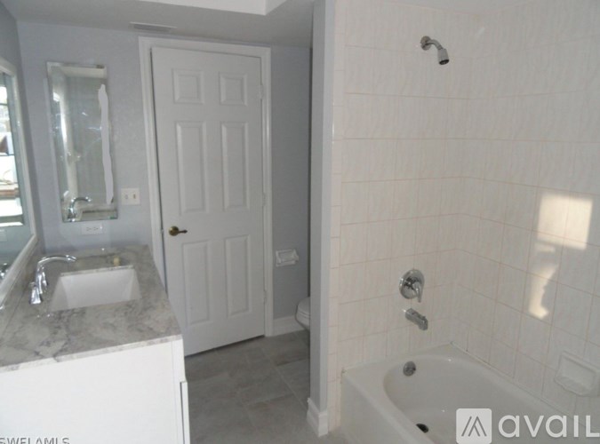 A white bathroom with a tub, sink, and mirror.