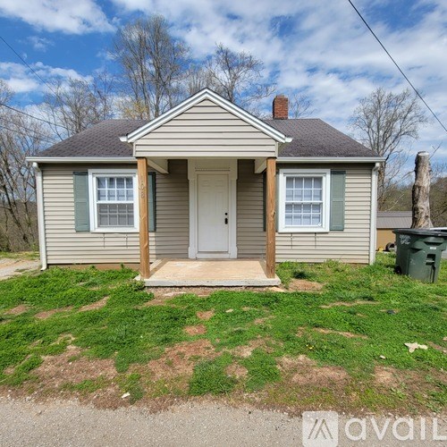 A small house with a grey roof and a white door is for sale.