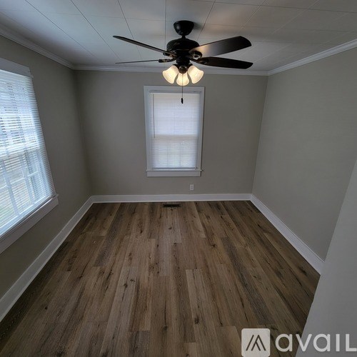 A room with a ceiling fan and wooden flooring.