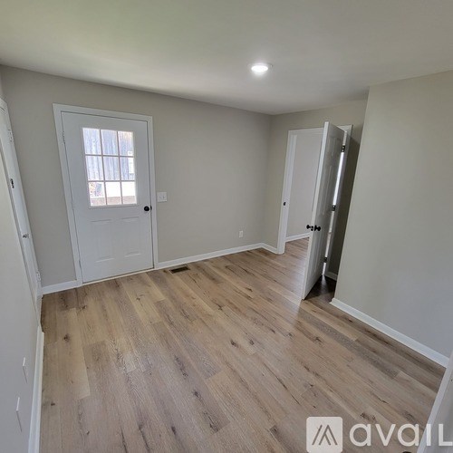 A room with a white door and wooden flooring.