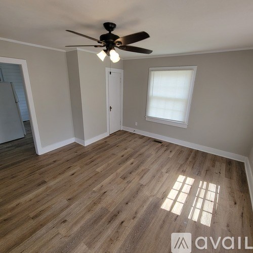 A room with a ceiling fan and wooden flooring.