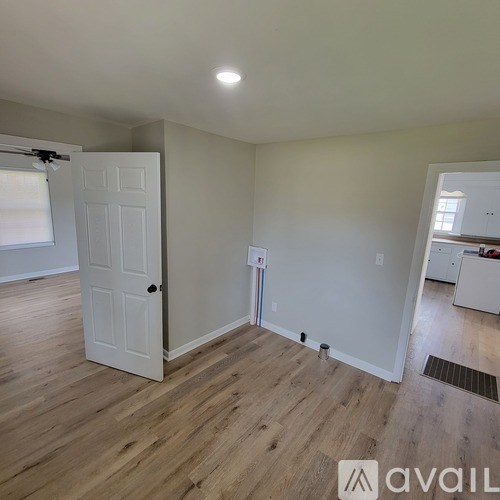 A room with a white door and wooden flooring.
