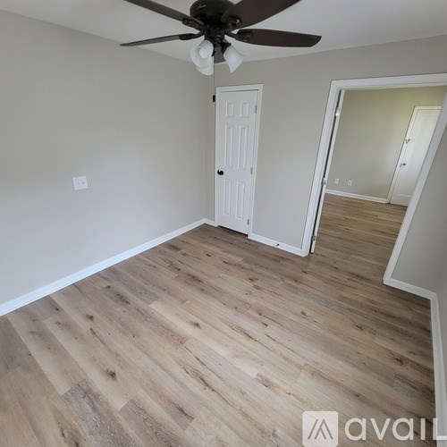 A room with a ceiling fan and wooden flooring.