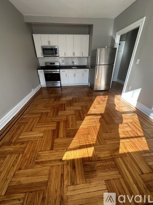 A kitchen with wooden flooring and white cabinets.