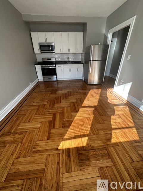 A kitchen with wooden flooring and white cabinets.