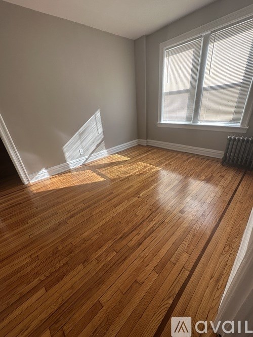 A room with wooden flooring and a window with blinds.