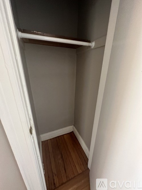 A small, empty room with a wooden floor and white walls.