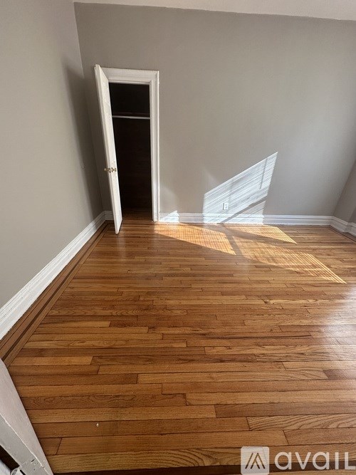 A room with wooden flooring and a doorway leading to another room.